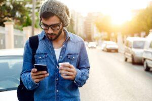 Man holding coffee while searching for single girls using his smartphone